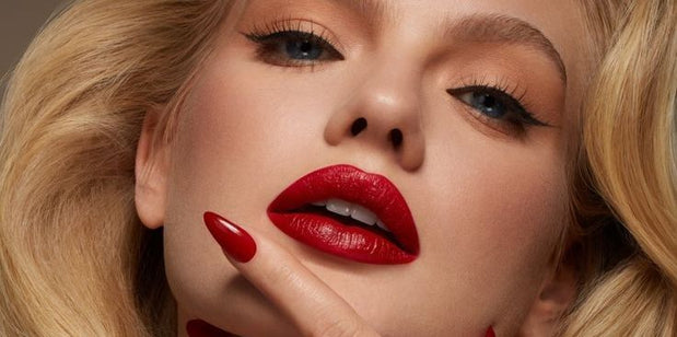 alt="Portrait of woman with golden curls, red lips, and blue eyes, accentuated by bold makeup"