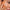 alt="Woman with brown eyes and voluminous lashes, her orange nails gently touching beige foundation on her cheek, against a solid backdrop"